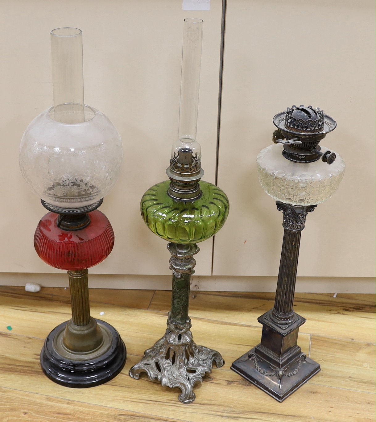 A Victorian plated oil lamp with glass reservoir, together with two others
